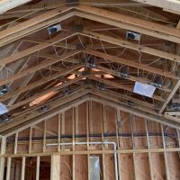 `A vaulted ceiling under construction, with ceiling boxes and low-voltage cable runs installed before the drywall goes up.`