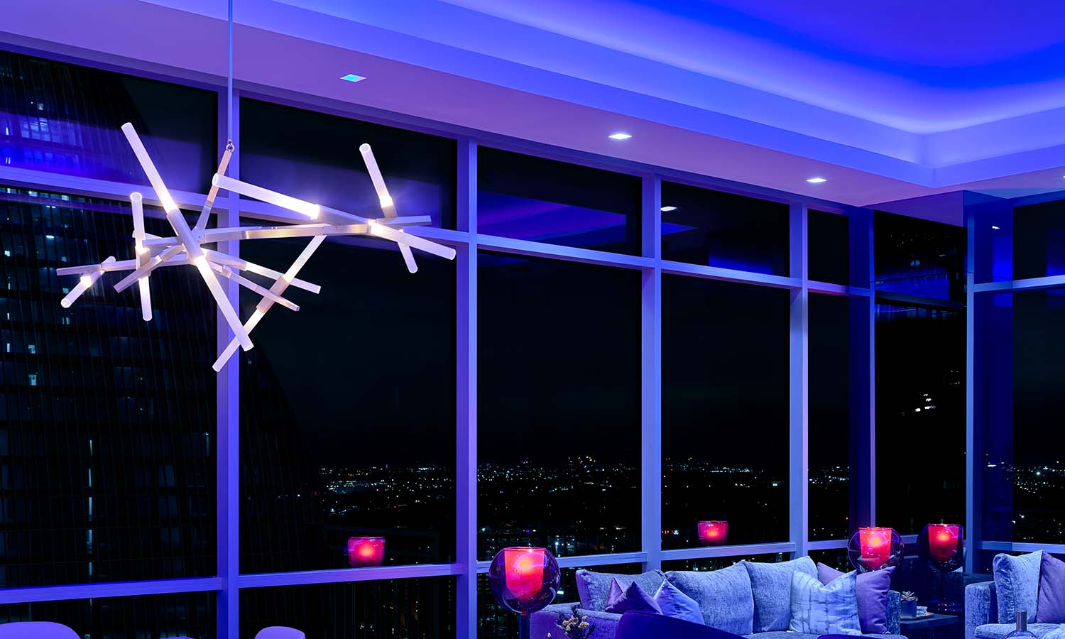 Modern living room with blue smart lighting and city view at night