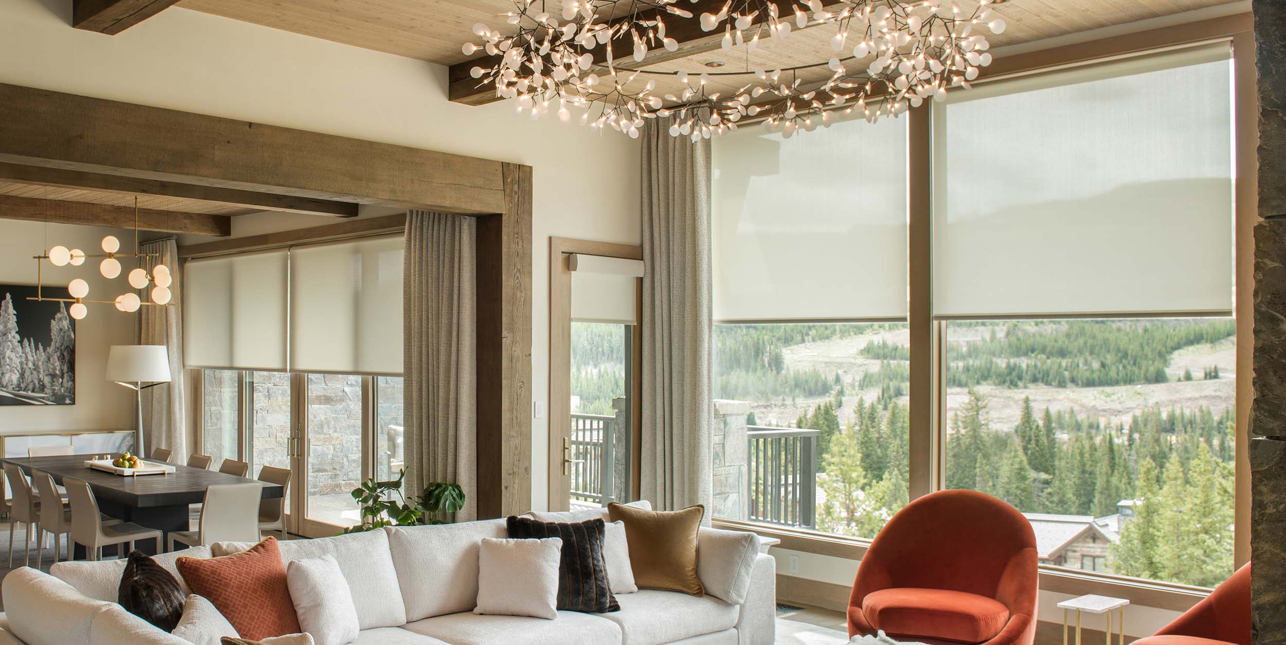 Living room with roller shades and drapes highlighting outdoor mountain views