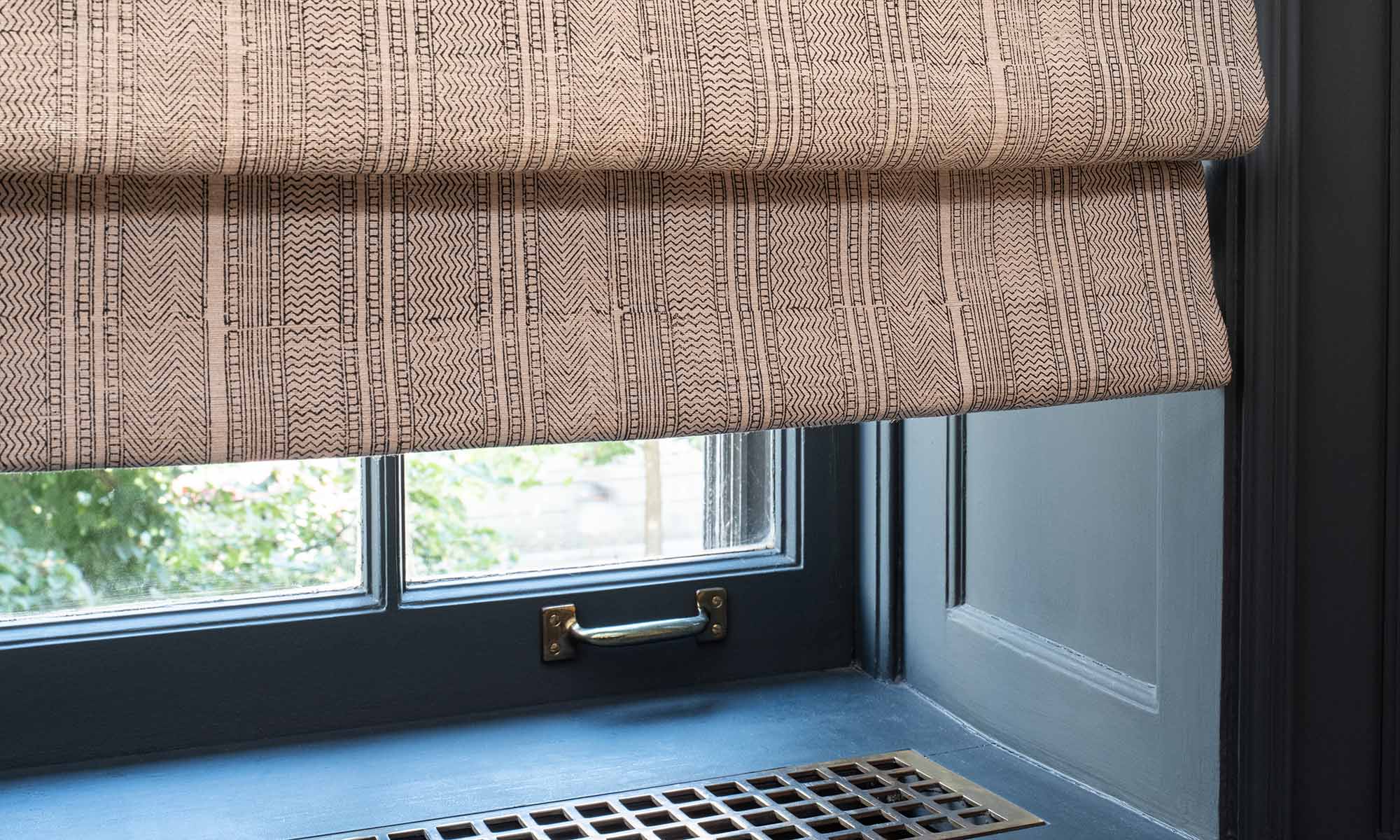 Close up of patterned roman shade fabric above a window