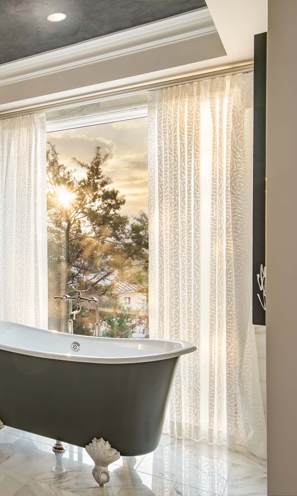 Bathroom with sheer patterned drapery beside a freestanding tub