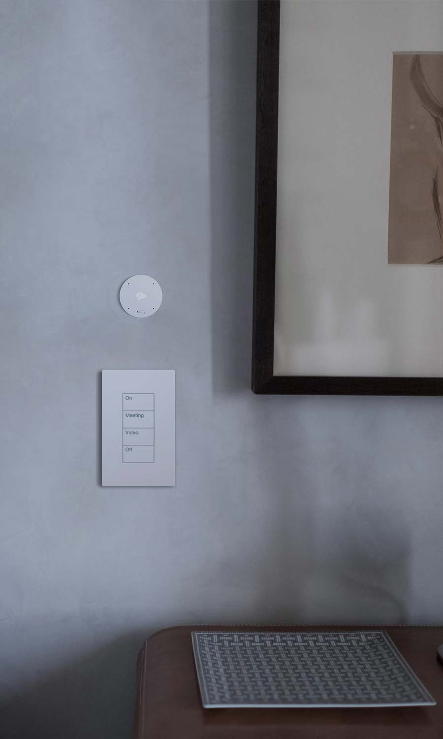 Wall keypad and small round control mounted near framed artwork
