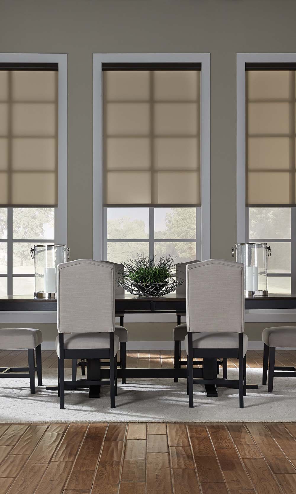 Dining room with three large windows featuring beige roller shades