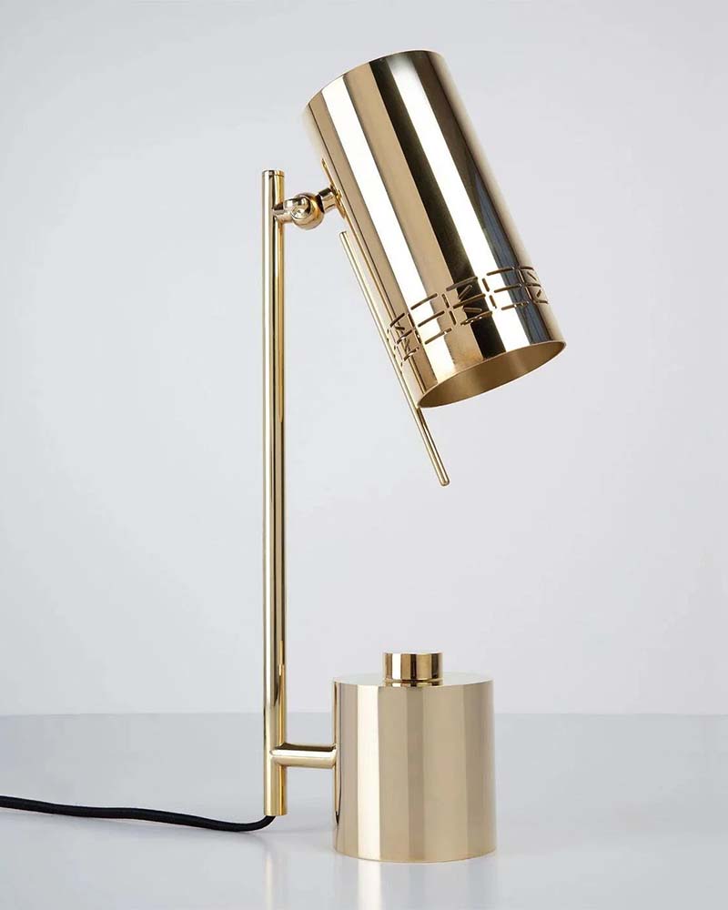 Brass table lamp with cylindrical shade on a white surface
