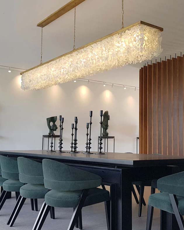 Dining room with long sculptural chandelier above dark wood table