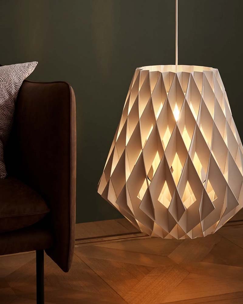 Geometric pendant lamp glowing beside a dark green wall