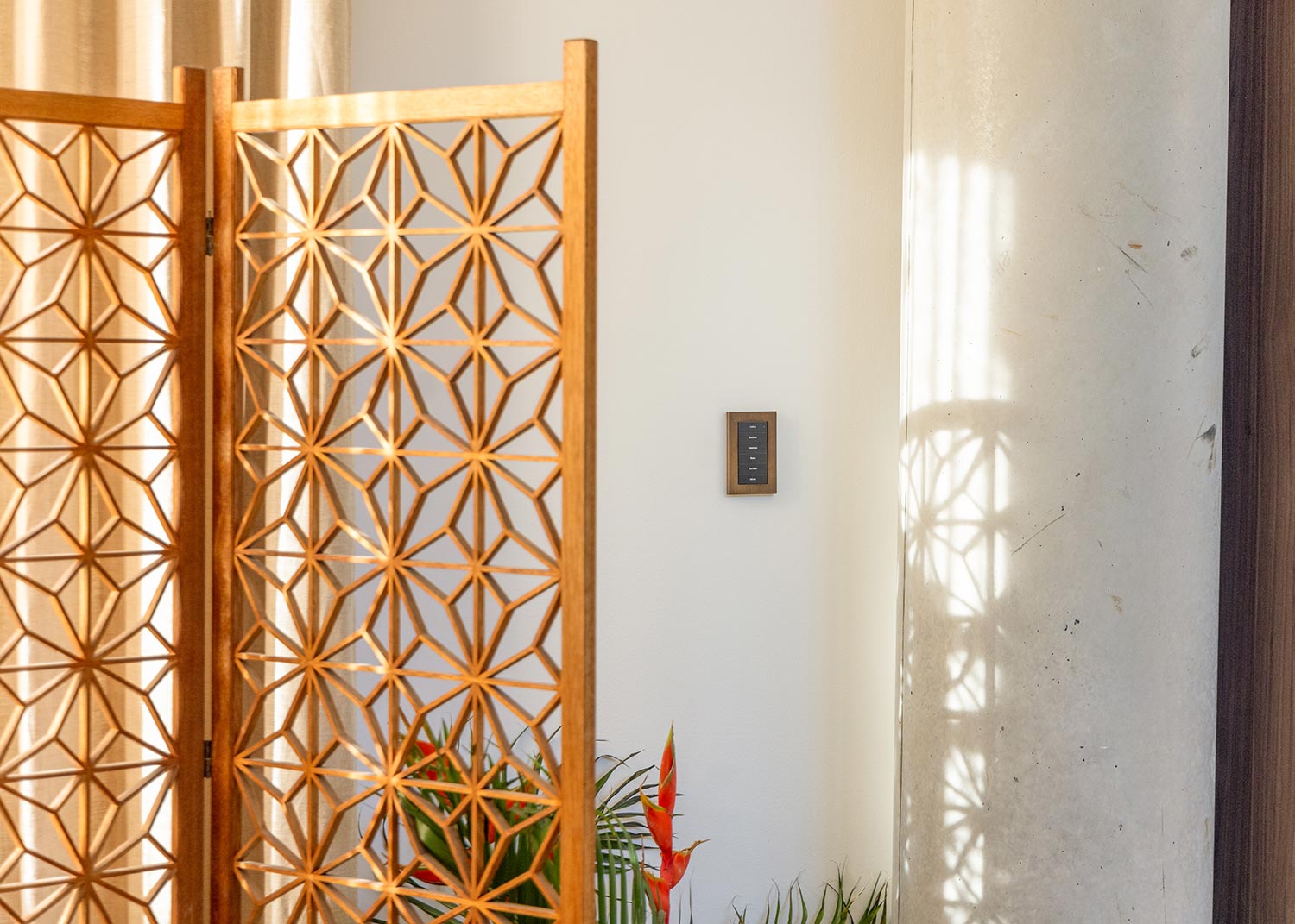 Decorative wooden screen beside wall with mounted smart light switch