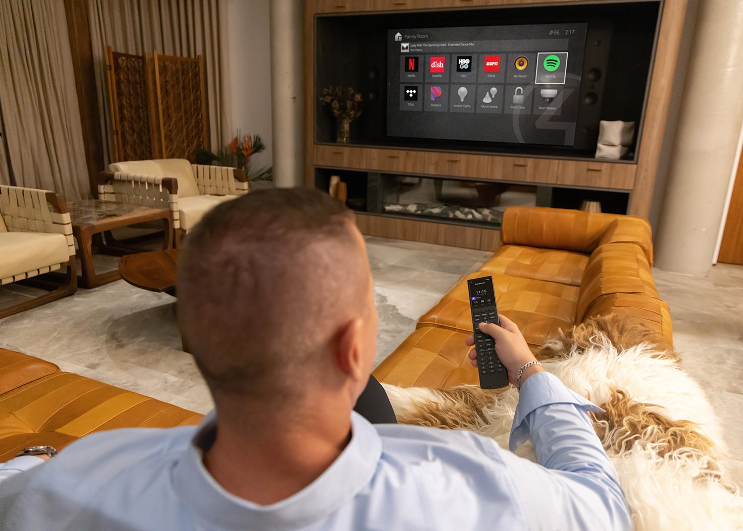 Man using smart remote control to watch streaming apps on large wall-mounted TV
