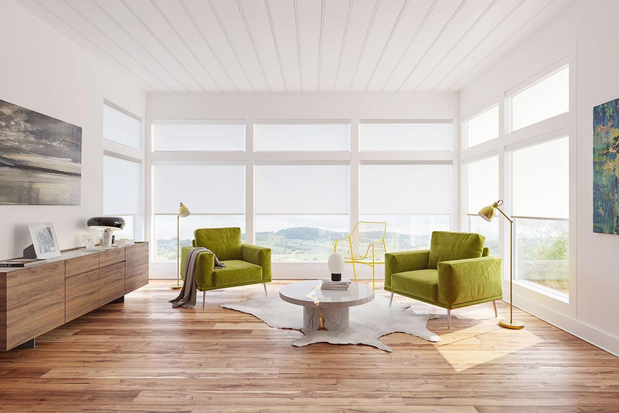 Bright lounge with green chairs and large windows covered by white shades