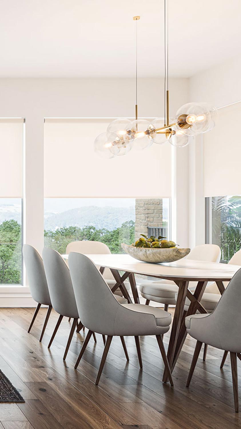 Bright dining room with modern chandelier and large windows with shades