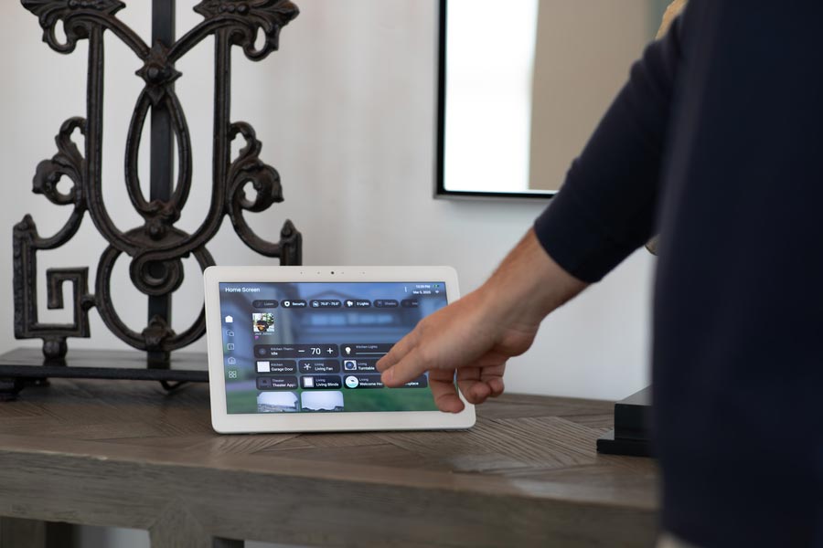 Person tapping a touchscreen control panel with Control4 smart home interface.