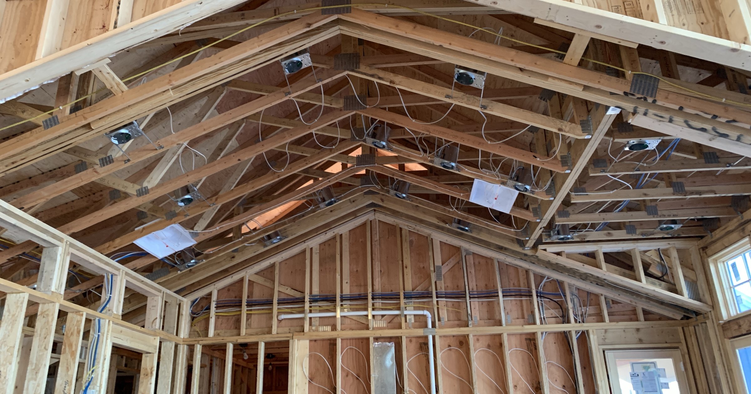 `A vaulted ceiling under construction, with ceiling boxes and low-voltage cable runs installed before the drywall goes up.`