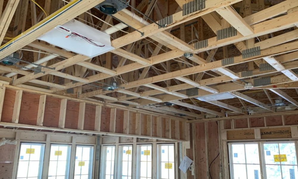<span class="uk-h4">Open framed room during new construction, with exposed ceiling trusses, low-voltage wiring, speaker rough-in brackets, and junction boxes visible before drywall.</span>