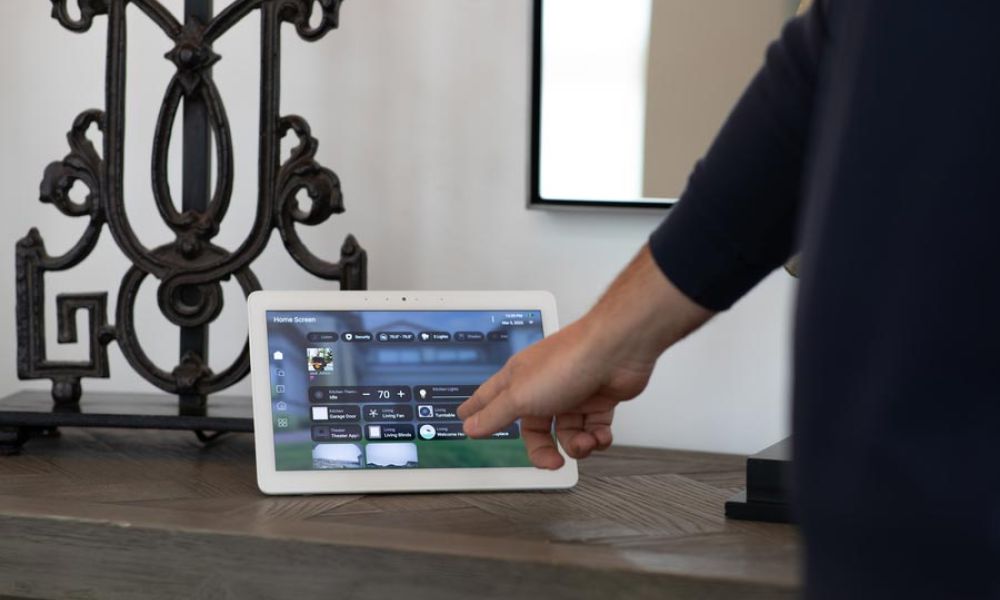 <span class="uk-h4">Person tapping a touchscreen control panel with Control4 smart home interface.</span>