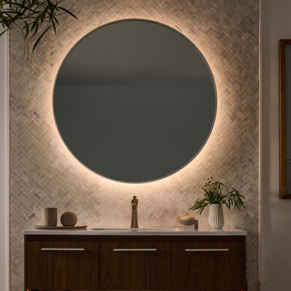 Round backlit mirror above a vanity with warm ambient lighting